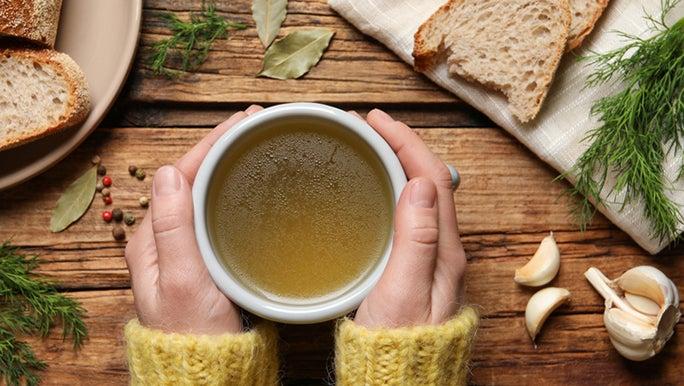 A pair of hands around a cup of bone broth, which is considered good for gut health